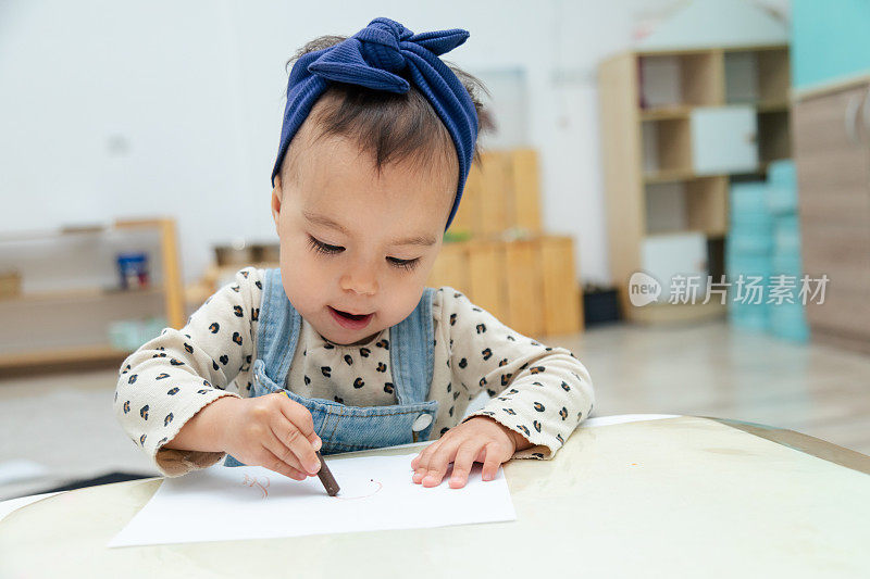 蹒跚学步的孩子用油笔在纸上写字