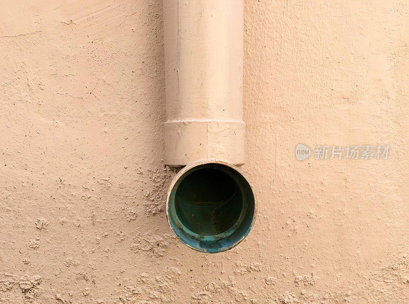 一根管子从墙上伸出来，还有一根绿色的管子从墙上伸出来，有一根管子连着墙。