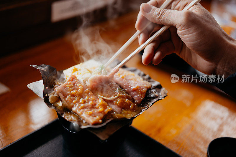 一名男子在餐厅里吃着飞田牛肉河豚味噌