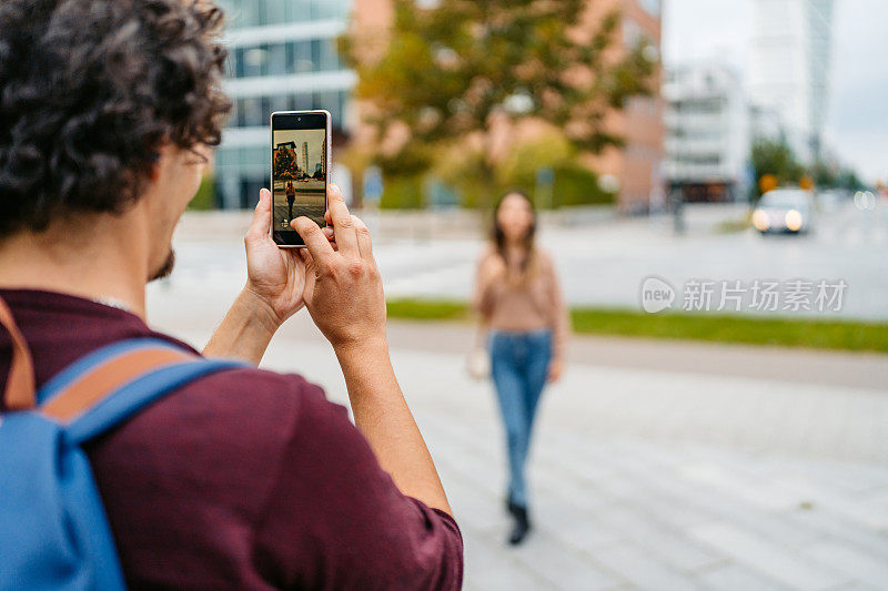 在瑞典马尔默的大街上，一个年轻人正在给他的女朋友拍照