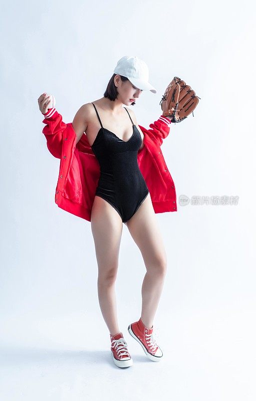 一位戴着棒球帽、穿着紧身衣、穿着运动鞋的妇女拿着棒球和棒球手套