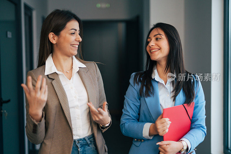 两个年轻的女商人在商业走廊里聊天