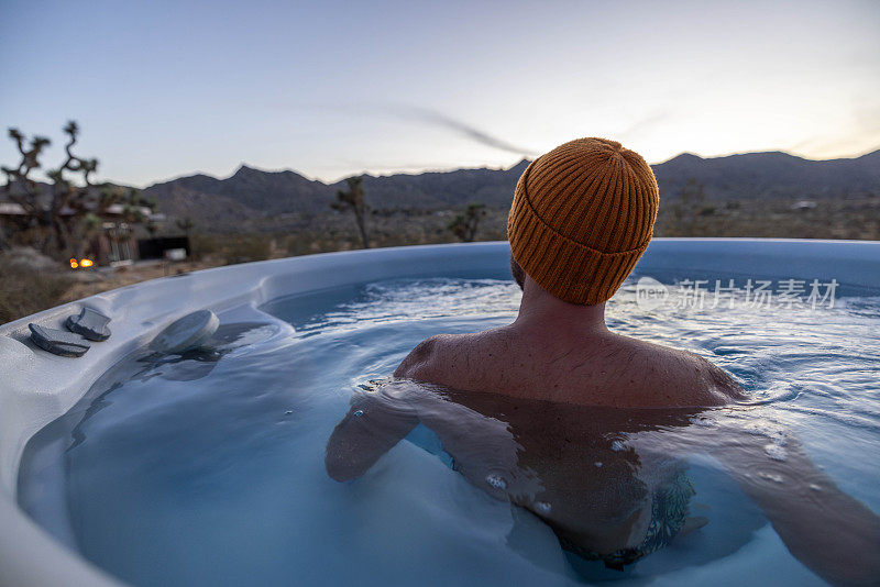 黄昏的宁静:一个男人的宁静浸泡在户外按摩浴缸心爱的风景