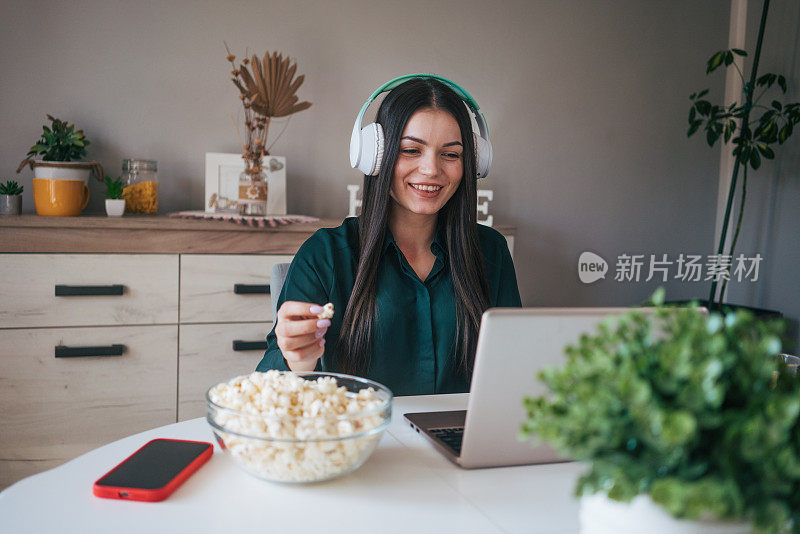 一个年轻女子一边看电影一边吃爆米花。