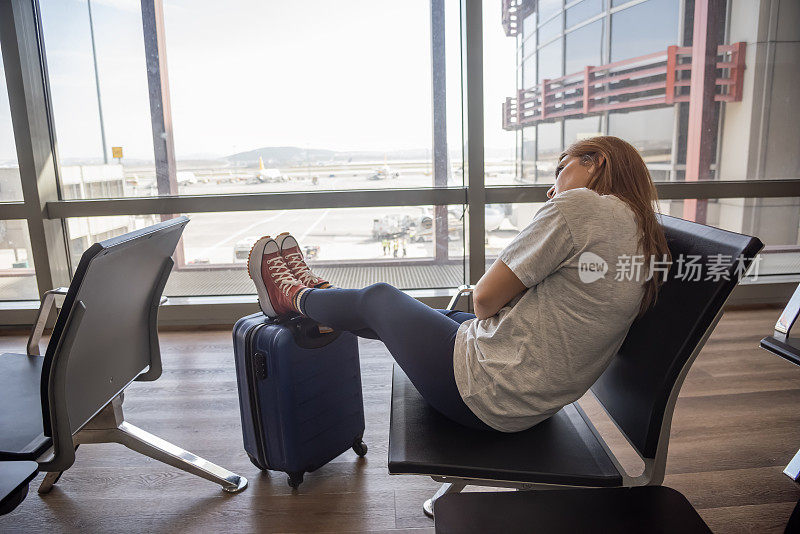 一位美丽的年轻女子坐在国际机场的大厅里等待她的航班