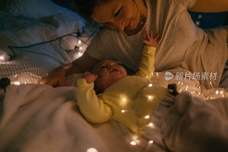 母亲和新生儿躺在床上，圣诞的气氛