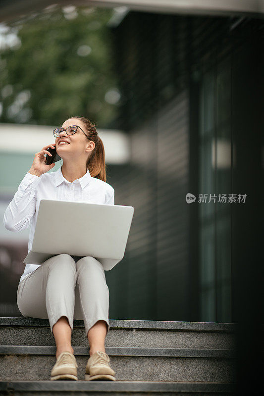 年轻漂亮的女商人一边打电话一边喝咖啡