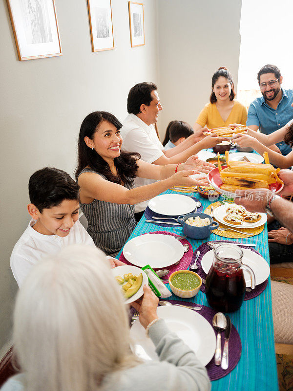 快乐的墨西哥家庭坐在一起，提供食物