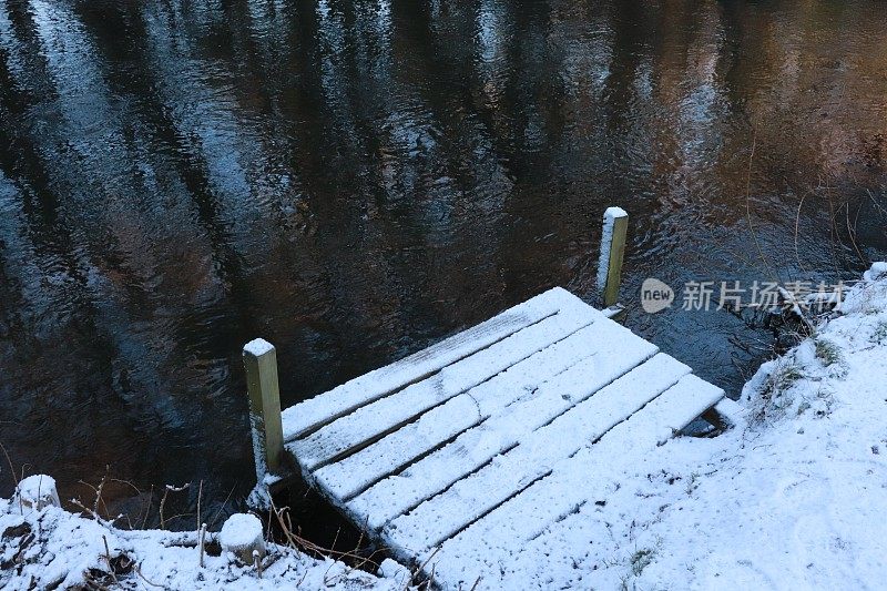 河边白雪覆盖的小木墩