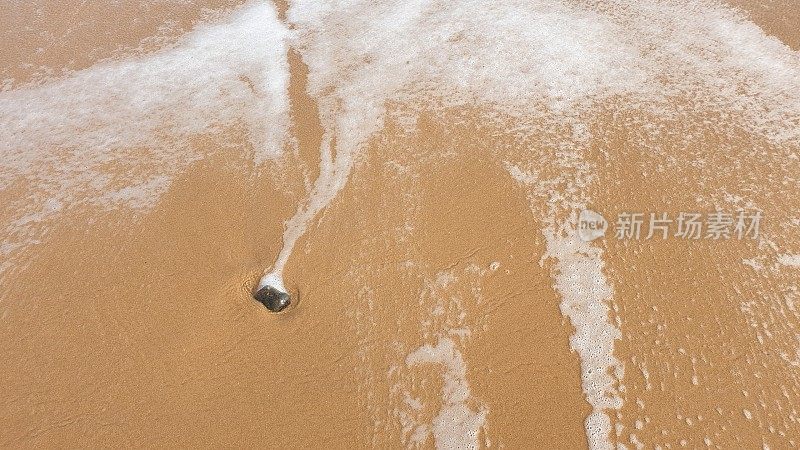 海水中的卵石在沙滩上激起泡沫