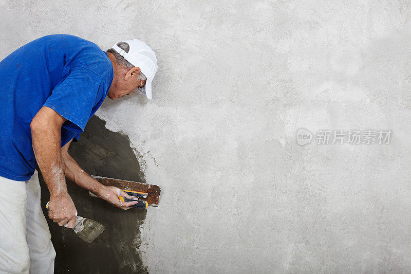 熟练的建筑大师用抹灰刀在干墙上工作