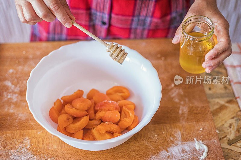 杏馨香果挞准备，将蜂蜜加到新鲜杏片上，搅拌均匀
