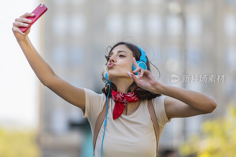 一名年轻女子正带着她的智能手机走在城市的路上