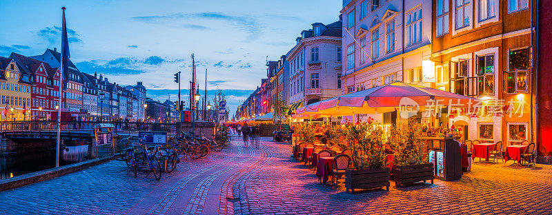 哥本哈根尼哈芬繁忙的港口，酒吧，餐厅温暖地照亮黄昏全景丹麦