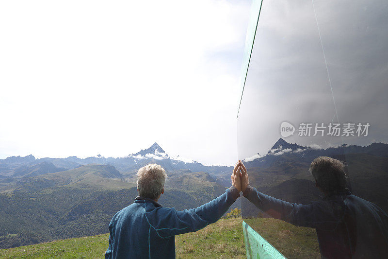 在山区草地上，一位老人靠在露营车上休息