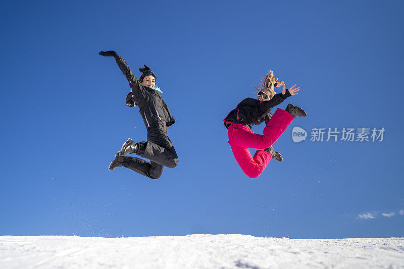 年轻的滑雪者在雪山上嬉戏跳跃