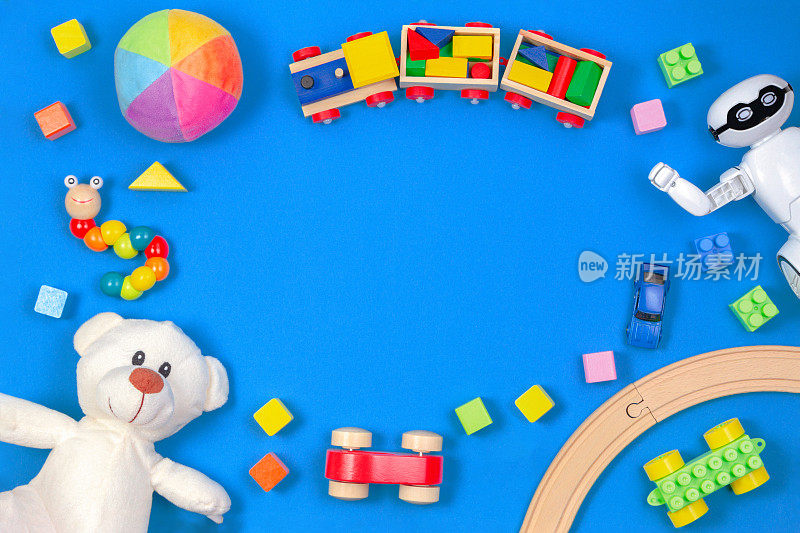 儿童玩具的背景。白色泰迪熊，木制火车，玩具汽车，机器人，彩色积木在蓝色背景