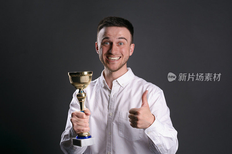 最佳员工奖。微笑的男人拿着金杯，翘着大拇指。企业竞争的赢家