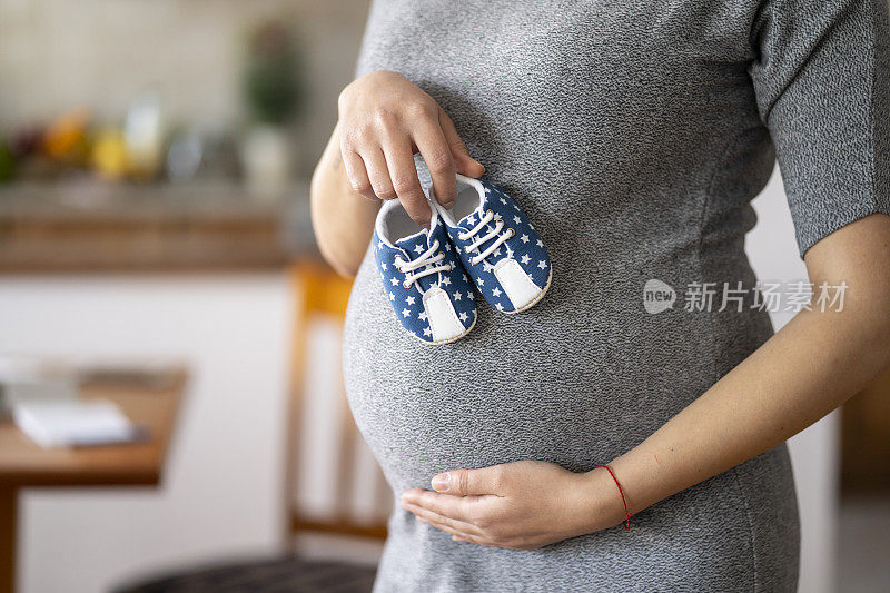 肚子上抱着男婴鞋的孕妇