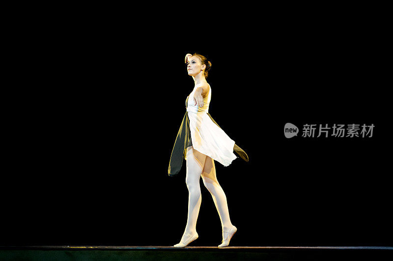 年轻女孩在黑色舞台上跳芭蕾舞