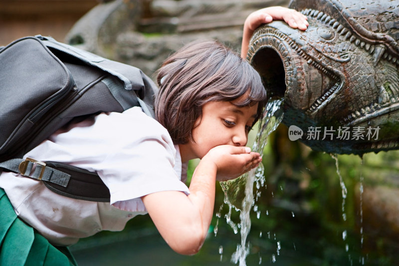 年轻的尼泊尔女孩在杜巴广场的城市喷泉中饮水