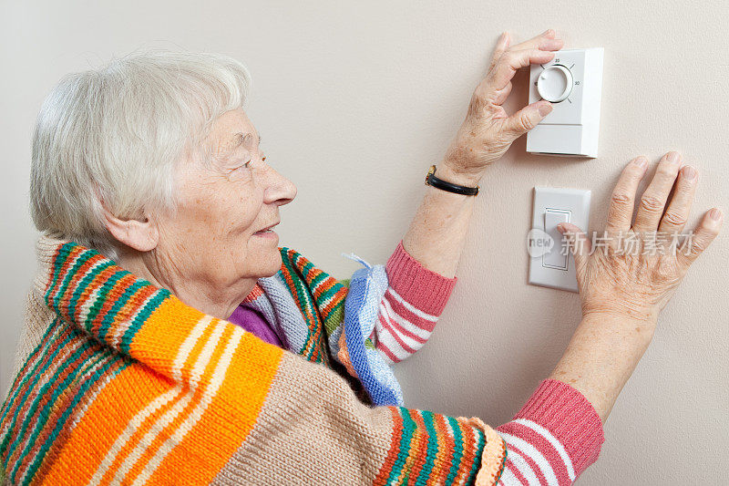 一位年长的女士正在调节恒温器