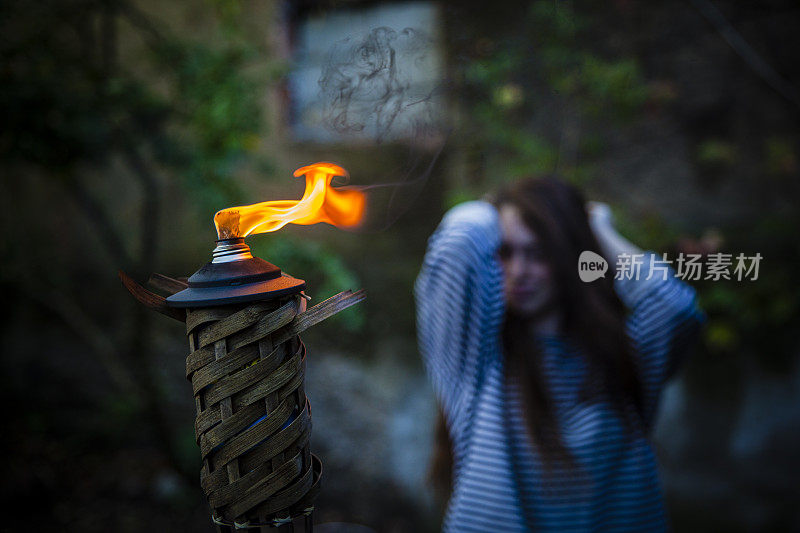 一个少女在花园里举着燃烧的火炬