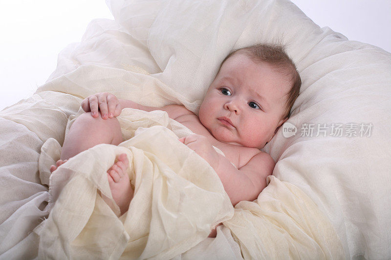 可爱而严肃的婴儿躺在白色浪漫的床上