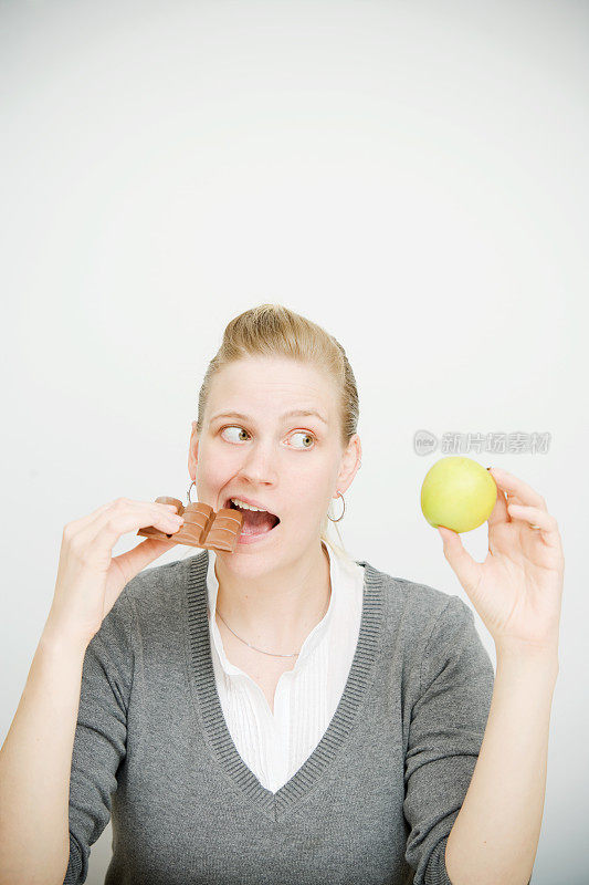 拿着巧克力和苹果的女人的饮食选择