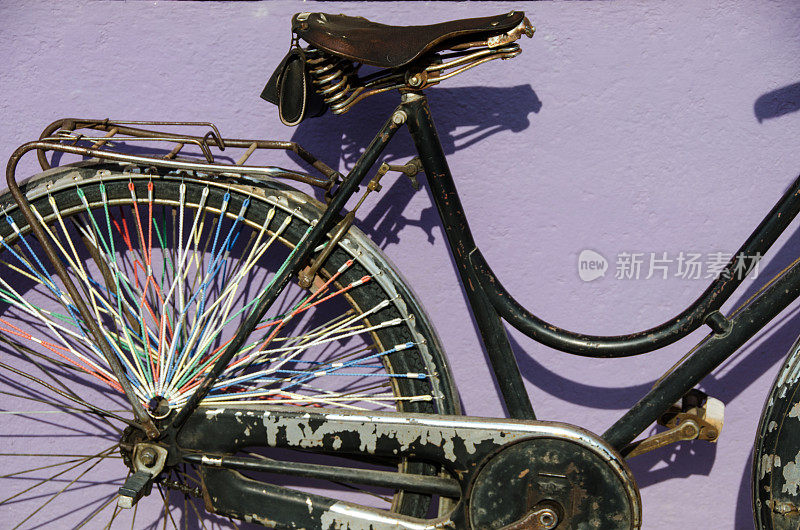一辆靠在紫色墙上的老式自行车
