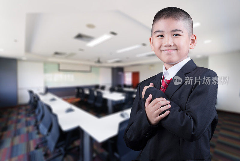快乐微笑的小商务男孩在会议厅的背景