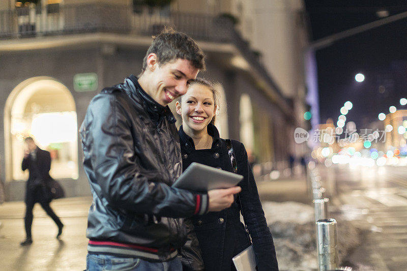 年轻的城市夫妇在街上使用数码平板电脑