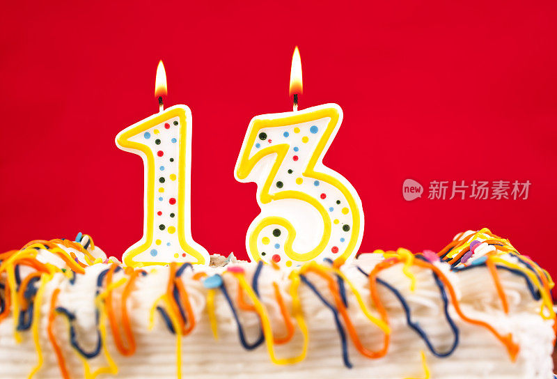 生日蛋糕装饰。13号燃烧的蜡烛。红色的背景。