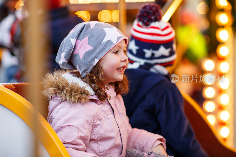 小男孩和小女孩，兄弟姐妹在圣诞市场的旋转木马上