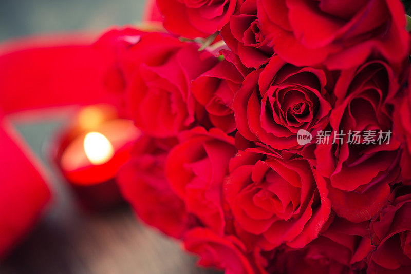 红色玫瑰和蜡烛在木制背景与丝带