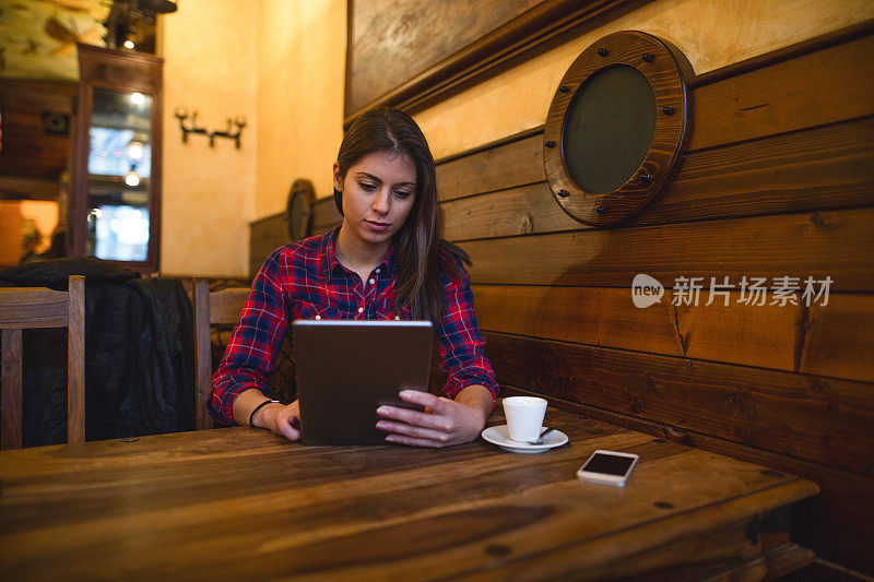 一名年轻女子在咖啡馆里使用平板电脑。