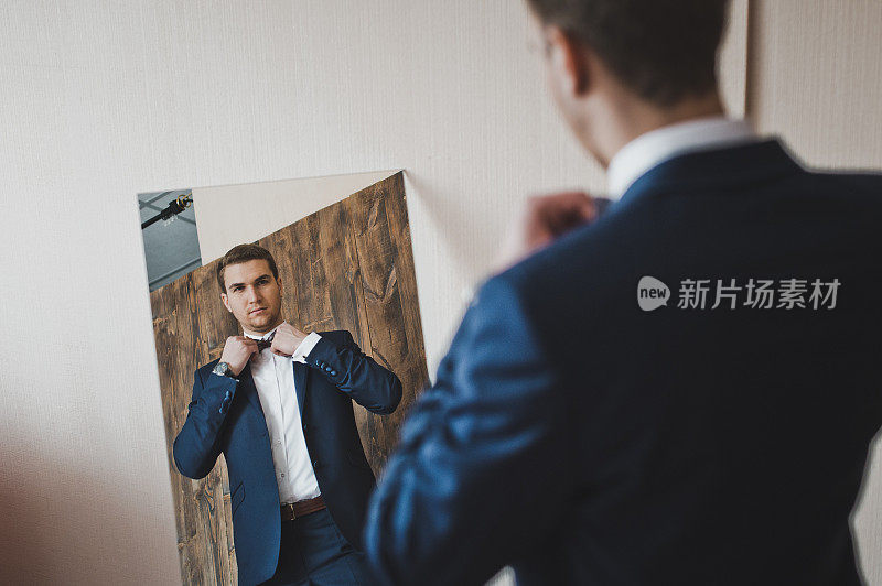 男人在镜子前欣赏自己的衣服。