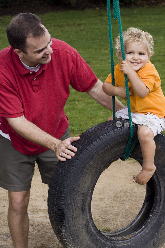 父亲和儿子一起玩轮胎秋千。