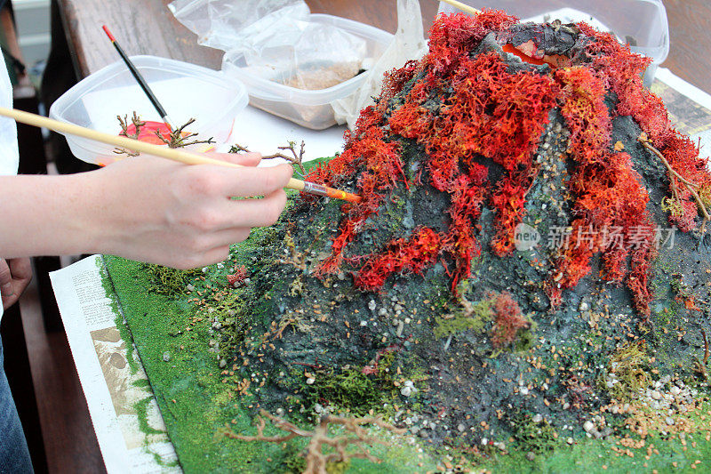 女孩画火山模型的图像，为学校项目制作