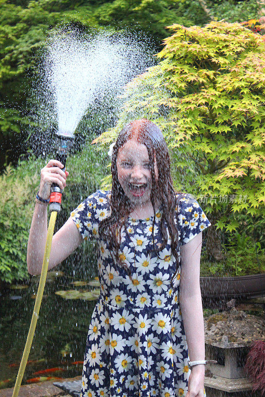 一个女孩用花园软管把自己浸泡在喷泉里