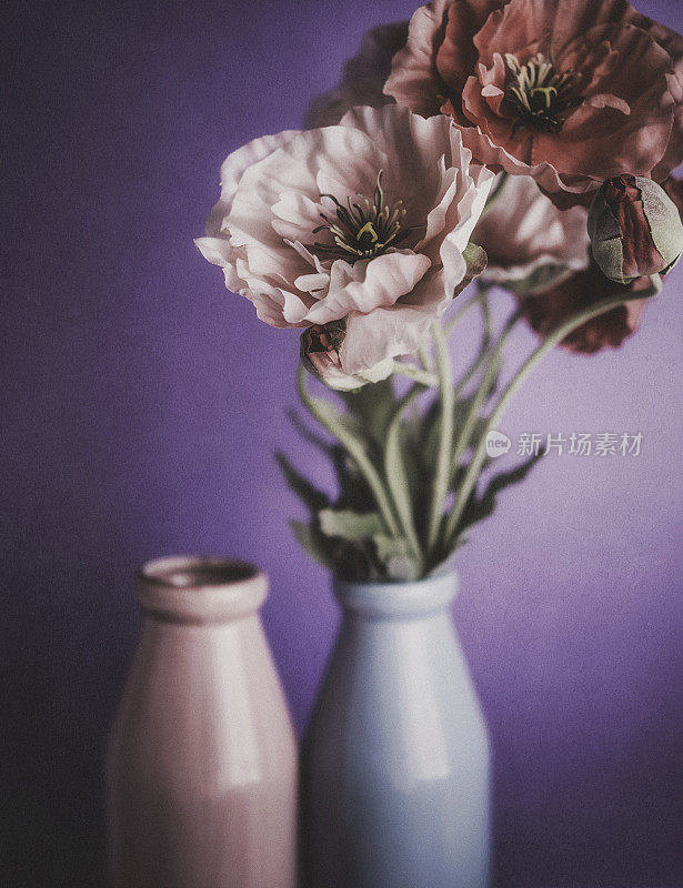 蓝色瓶子里的假罂粟花。静物画