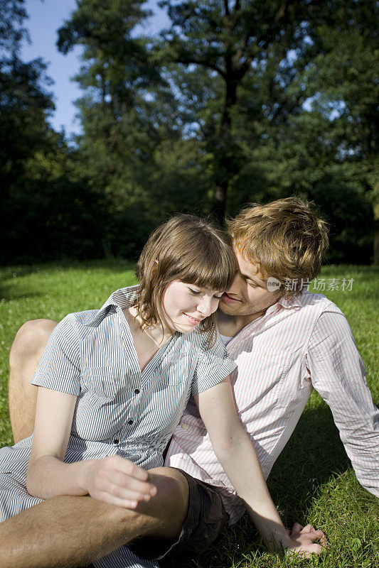 迷人而深情的年轻情侣坐在公园里