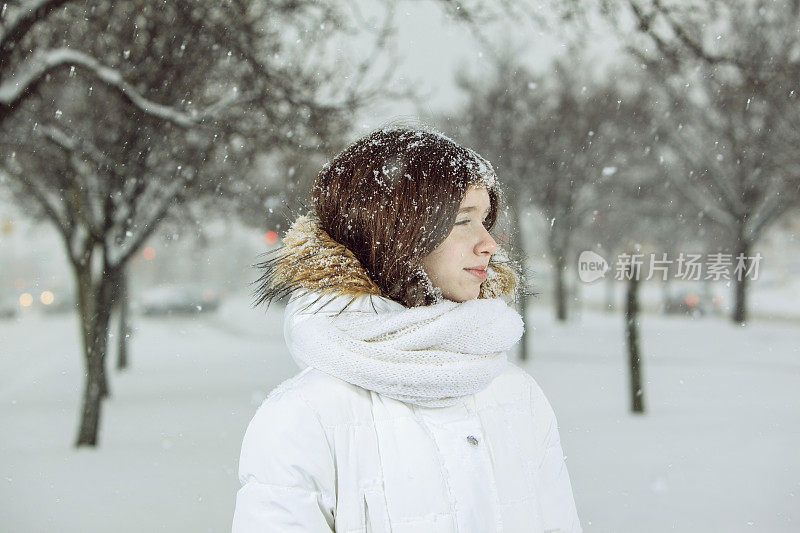 雪下穿着白色夹克的漂亮少女