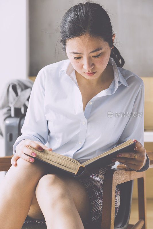 亚洲女商人在酒店房间里看书