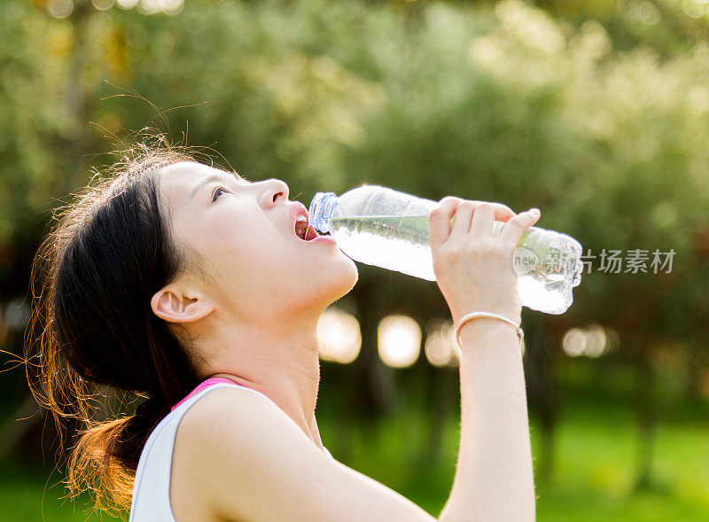 年轻女子在公园喝瓶装水
