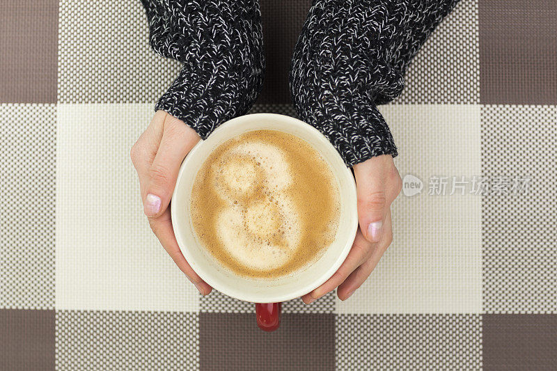 女人在咖啡杯旁暖手