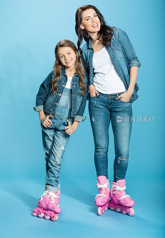 快乐的母亲和女儿在蓝色的工作室溜冰鞋