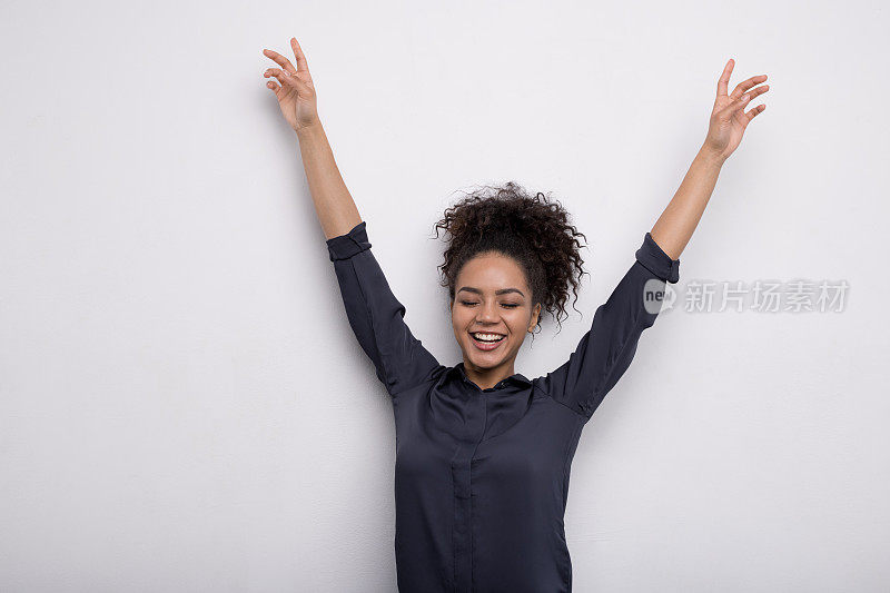 快乐的女人举起手，穿着一件衬衫