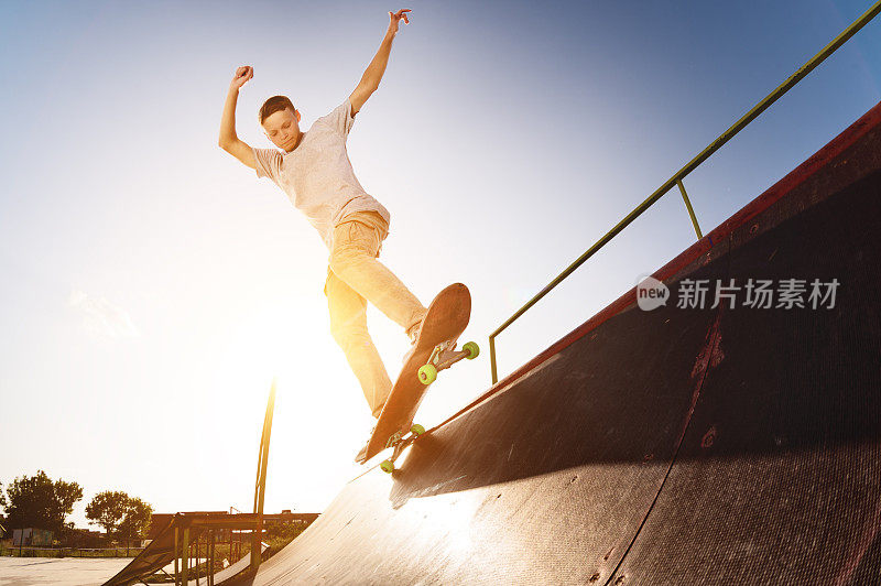 在一个滑板公园里，一个十几岁的滑板手挂在滑板的斜坡上