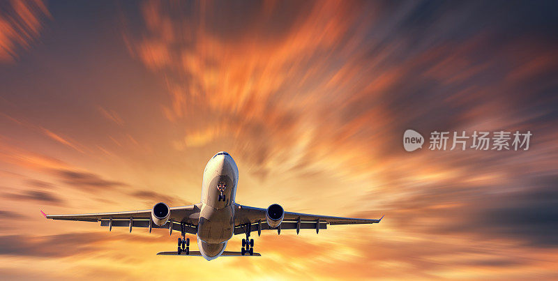 飞机和美丽的天空与运动模糊效果。落日时分，一架载有乘客的飞机在模糊的桔黄色天空中飞翔。客运班机。商用飞机。私人飞机